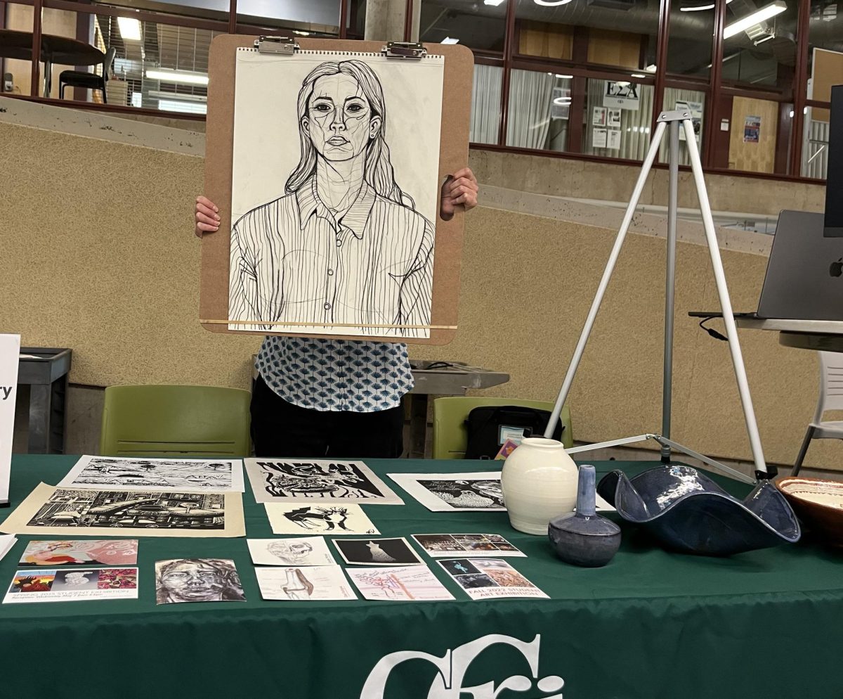 Heidi J. Jensen, Assistant Professor of Art holding student portrait.